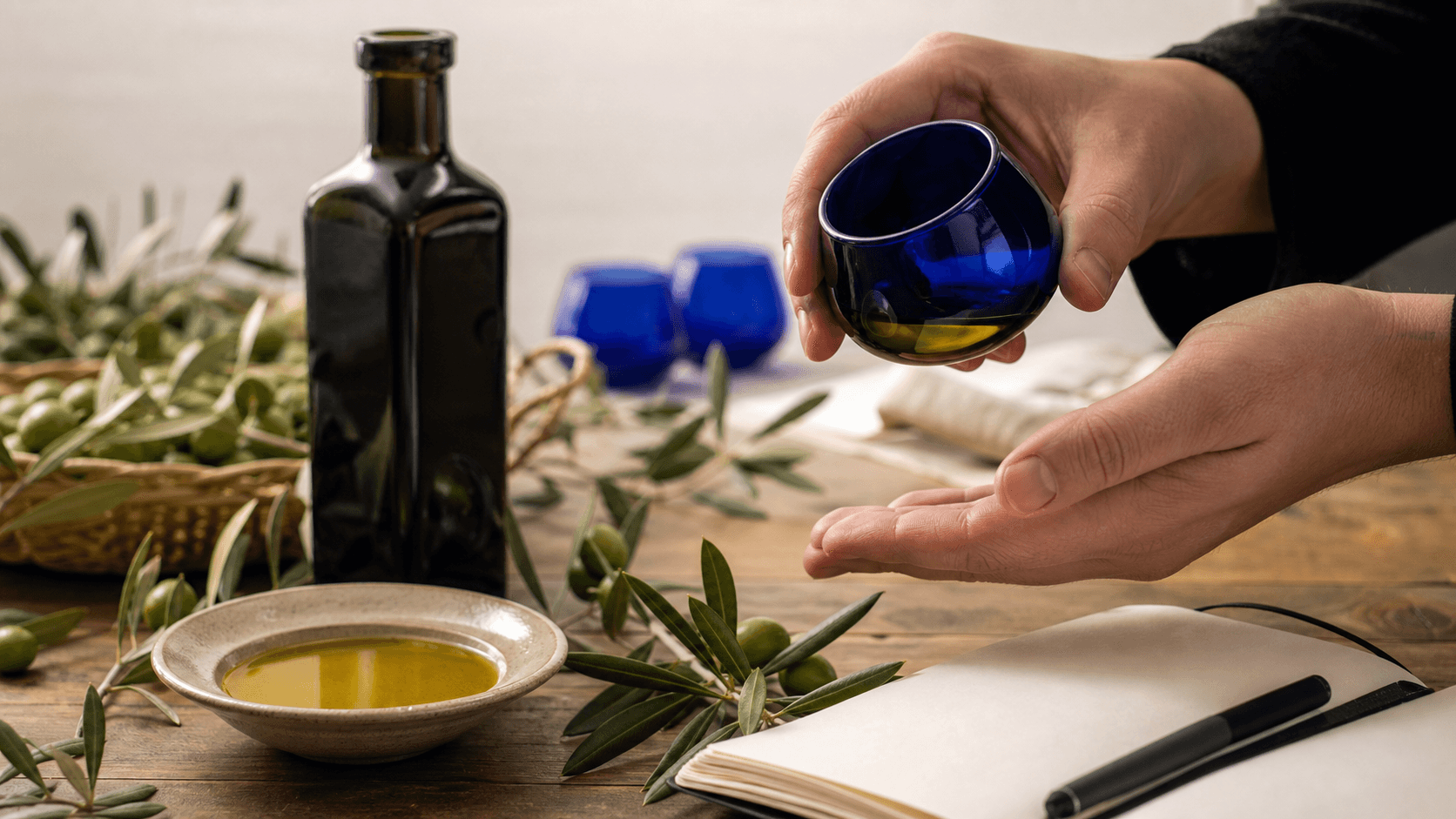 ارزیابی حسی روغن زیتون با فنجان چشایی آبی در کنار بطری تیره